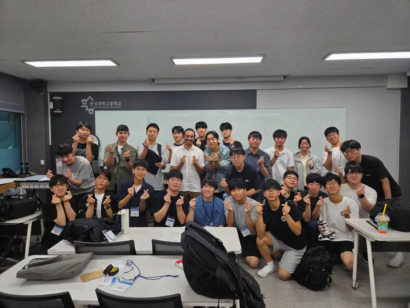 Karl with a large group of Korean high school students at Hansung Science High School, all making a finger-heart gesture