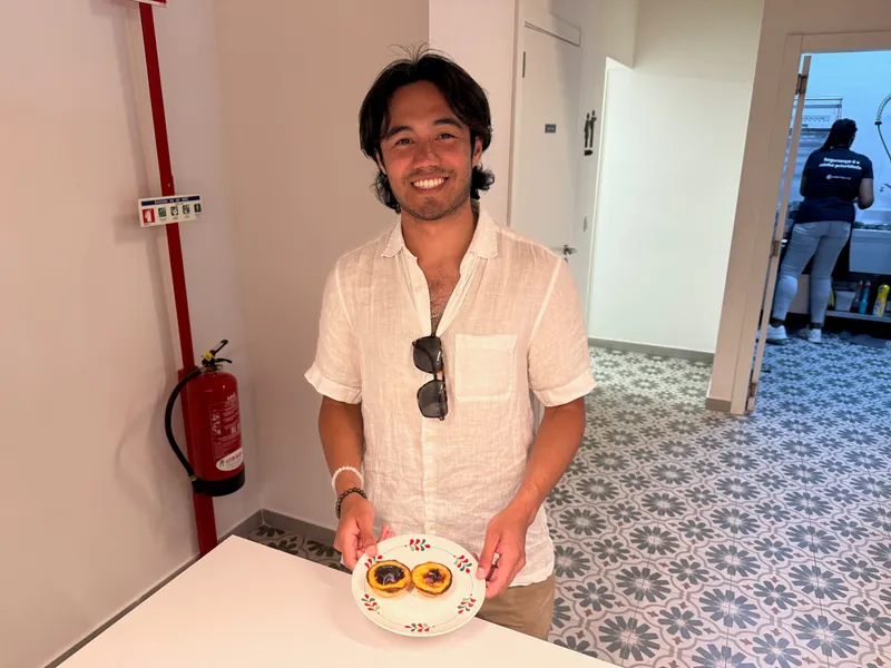 Karl holding a plate of two pasteis de nata in a Lisbon cafe