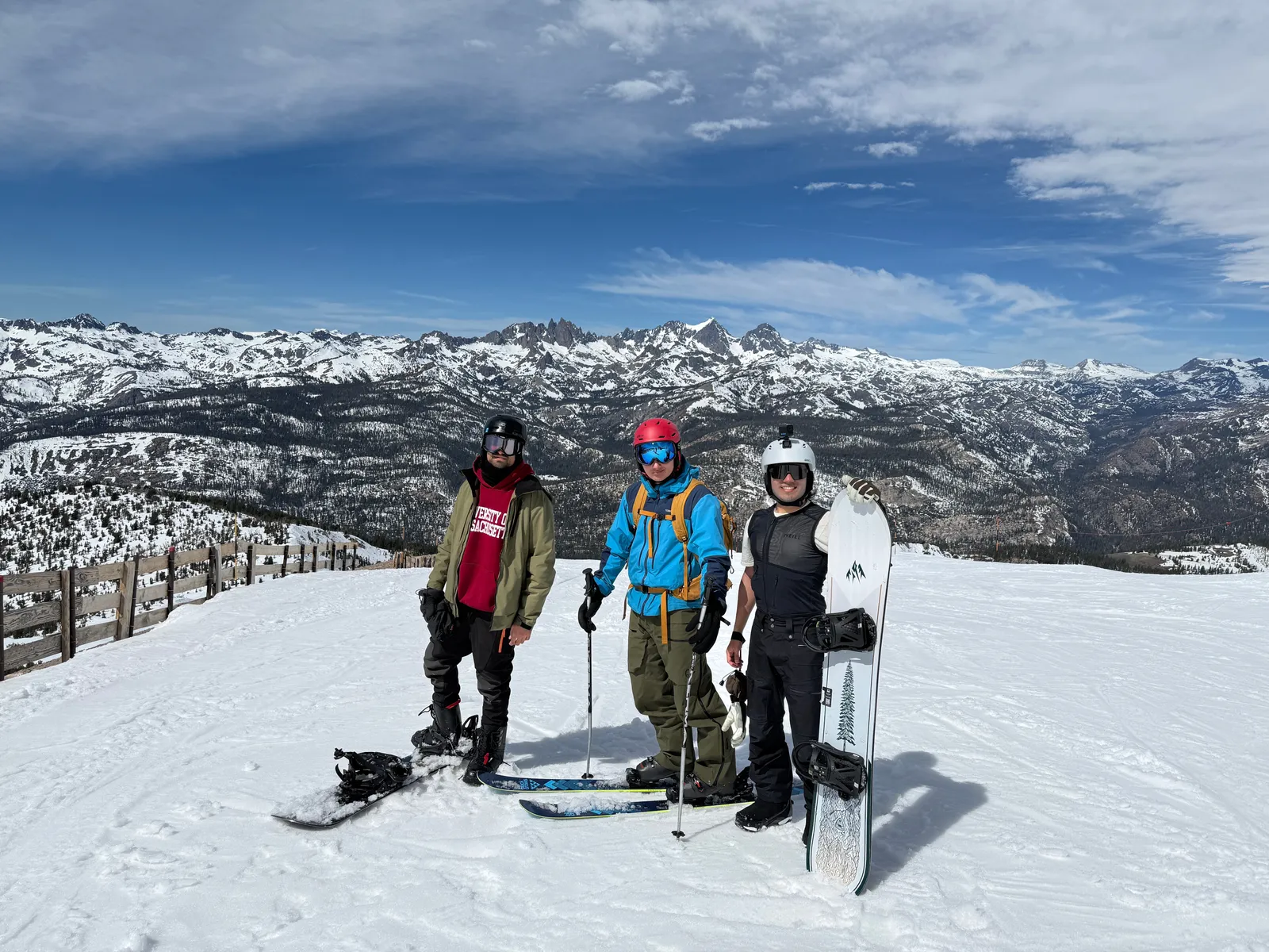 Three men at a snowy Mammoth, CA mountain summit with snowboards, granite peaks in the background
