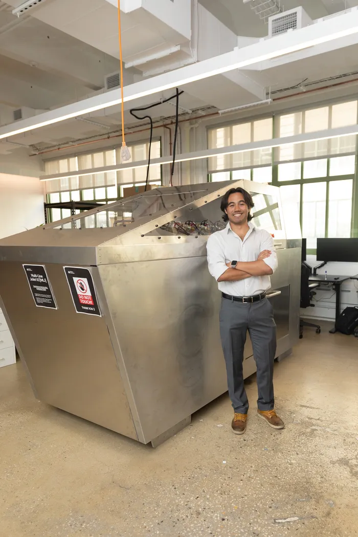 Karl standing arms-crossed in front of the Multi-Line Juliet V2 machine at the Mobius Industries workshop