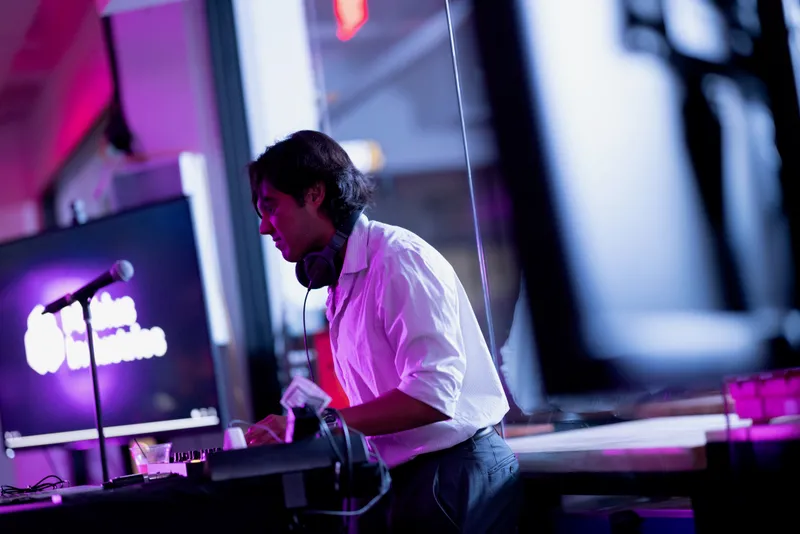 Side profile of Karl DJing at the Mobius Industries gala, purple event lighting