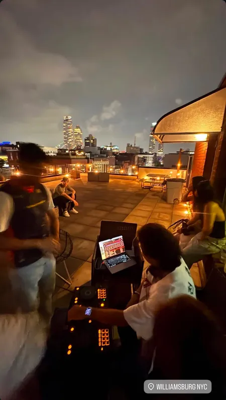 Karl DJing at a nighttime rooftop gathering in Williamsburg, Brooklyn